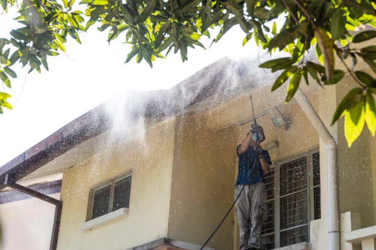 Worker using high pressure water jet spray gun to wash and clean dirt from roof ceiling